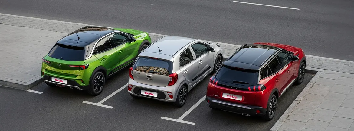 TikTak araç kiralama uygulaması ile uygun fiyatlı günlük araç kiralama seçenekleri: yeşil SUV, gri hatchback ve kırmızı crossover model araçlar yan yana park halinde görülüyor.
