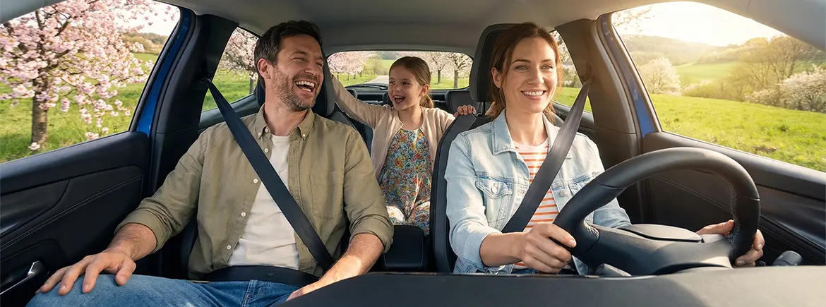 Güneşli bir yolda ilerleyen TikTak aracı içinde bayram tatilinin keyfini çıkaran gülen bir aile.