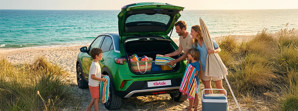 Yaz tatilinde ailesiyle sahil kenarında vakit geçiren kişiler, bagajına eşyalarını yerleştirirken TikTak ile kiralanmış araçlarını kullanıyor – yazlıkta uzun süreli konaklamalar için aylık araç kiralama ile ihtiyaçlara göre ideal çözüm.