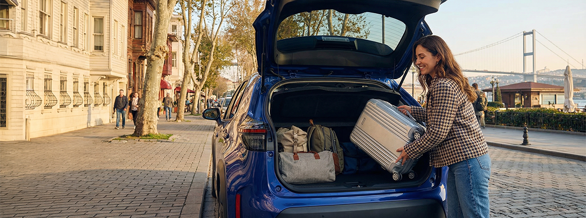 TikTak aracının bagajına valizlerini yerleştiren genç kadın,  rahatlamış bir şekilde gülümserken